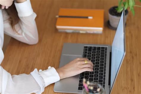 Nešiojamas kompiuteris ant stalo su kavos puodeliu ir užrašų knygele