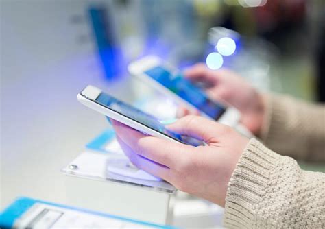 Žmogus, naudojantis mobilųjį telefoną atsiskaitymui parduotuvėje